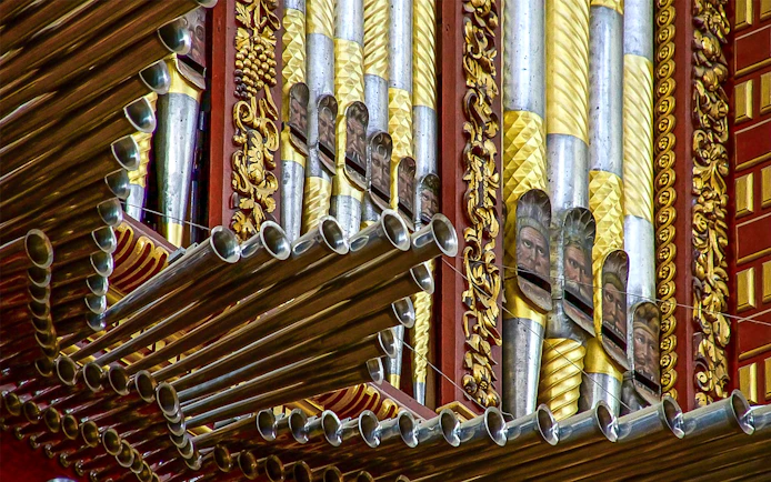 Ornate organ pipes inside Córdoba Cathedral-Mosque, featuring intricate gold and silver designs.