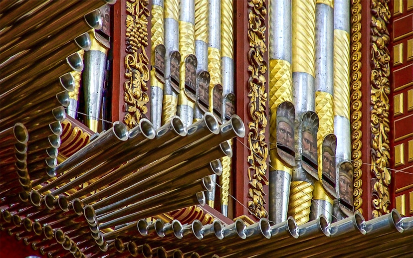 Ornate organ pipes inside Córdoba Cathedral-Mosque, featuring intricate gold and silver designs.