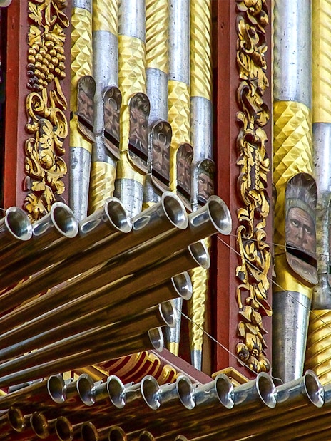 Ornate organ pipes inside Córdoba Cathedral-Mosque, featuring intricate gold and silver designs.