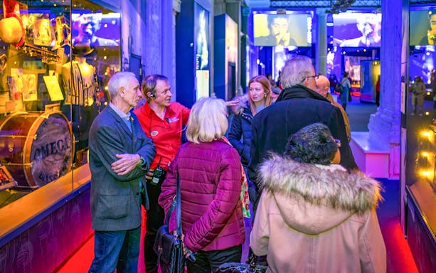 Group tour inside the British Music Experience, Liverpool, with guide explaining exhibits.