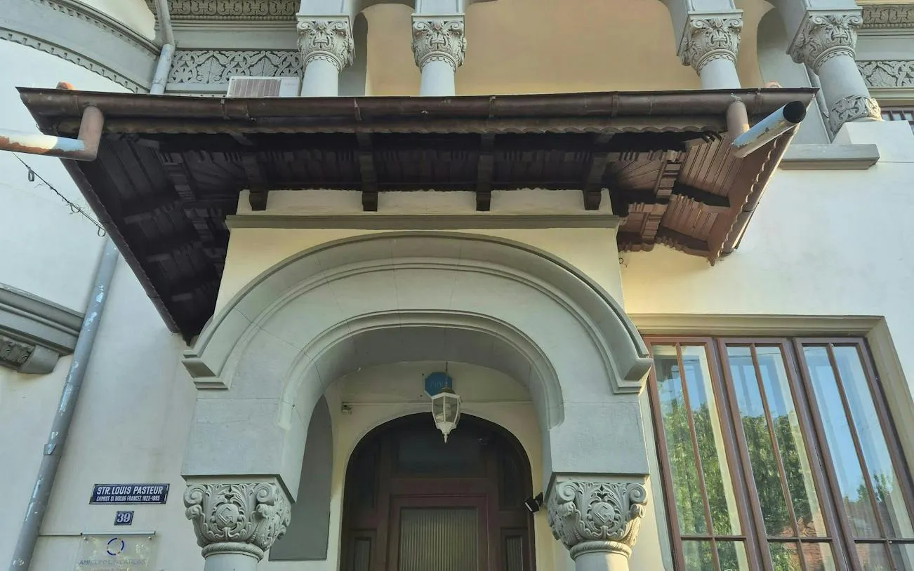 Ornate entrance of a historic building on Strada Louis Pasteur, Bucharest, featured in a self-guided city exploration game.