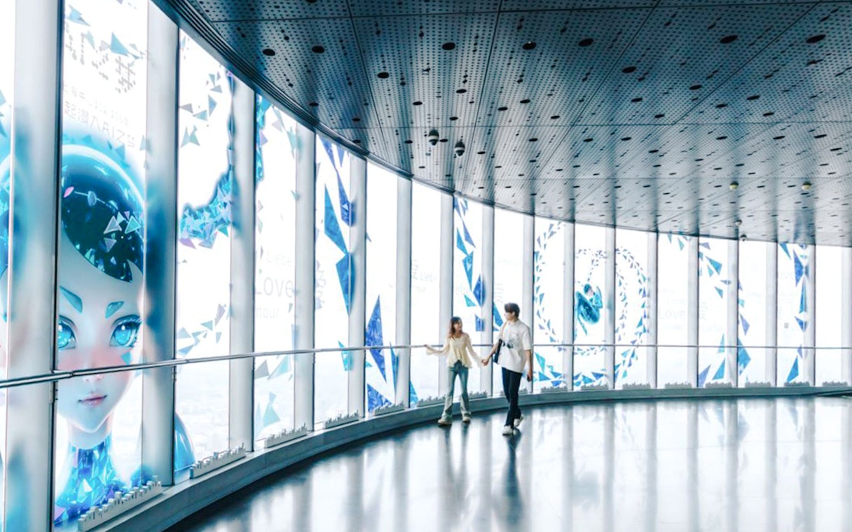 Visitors walking inside Shanghai Tower observation deck with digital art displays.