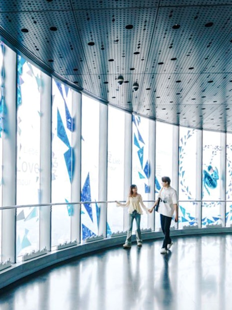 Visitors walking inside Shanghai Tower observation deck with digital art displays.