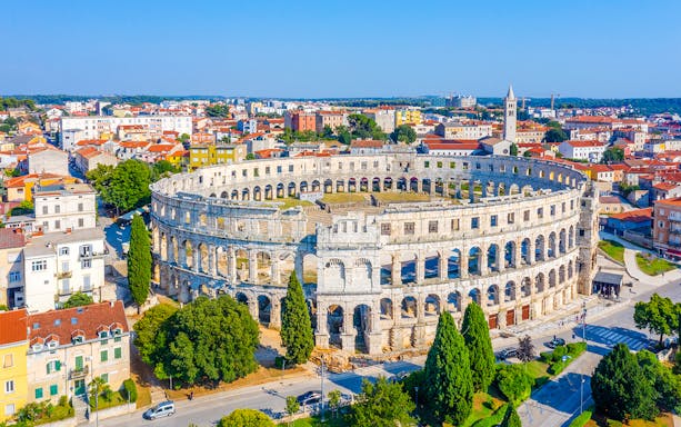 Roman Amphitheater in Pula, Croatia, surrounded by cityscape.