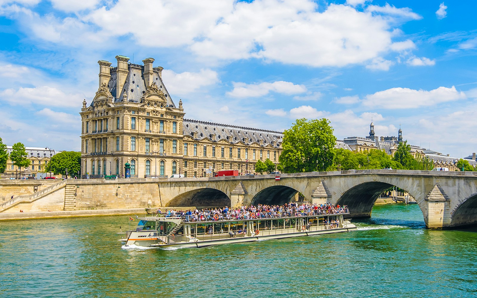 Louvre Musuem during noon as seen from Batauex Mouches, with another boat passing by.