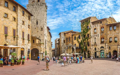 San Gimignano town square with medieval towers and tourists exploring during the day.