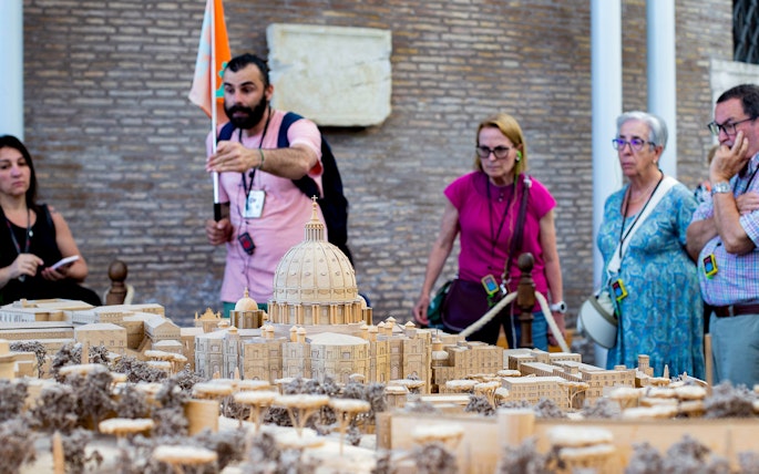 Tour group examining Vatican model at Vatican Museums, Rome.