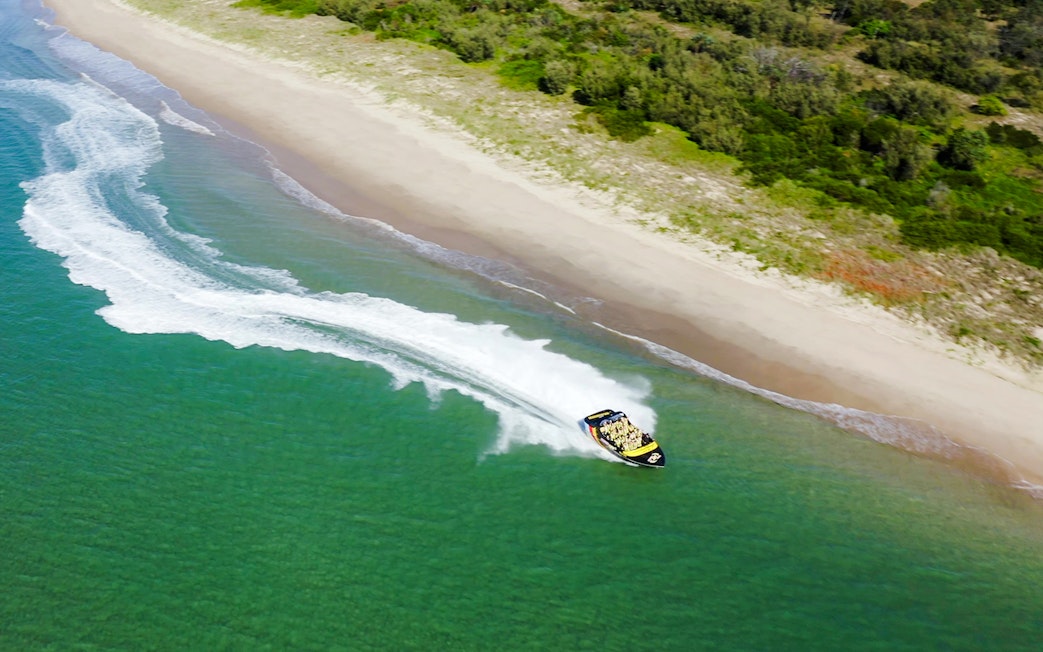Jet boat speeding along Gold Coast shoreline during 55-minute adventure ride.