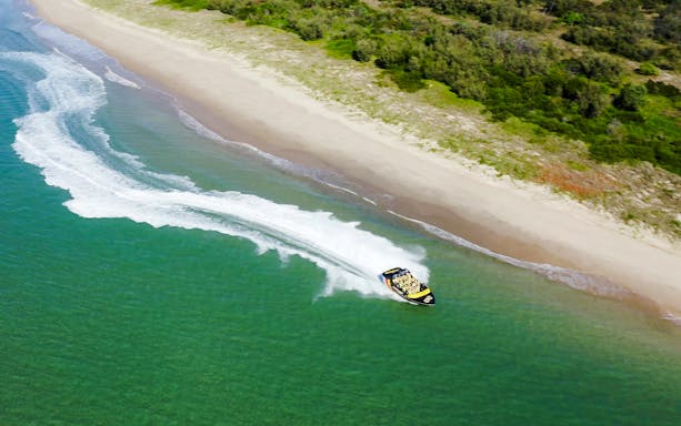 Jet boat speeding along Gold Coast shoreline during 55-minute adventure ride.
