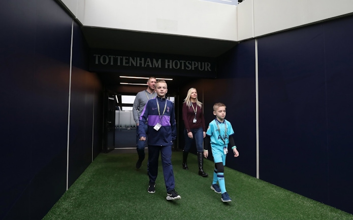 Visitors walking through the Tottenham Hotspur Stadium tunnel during a tour.