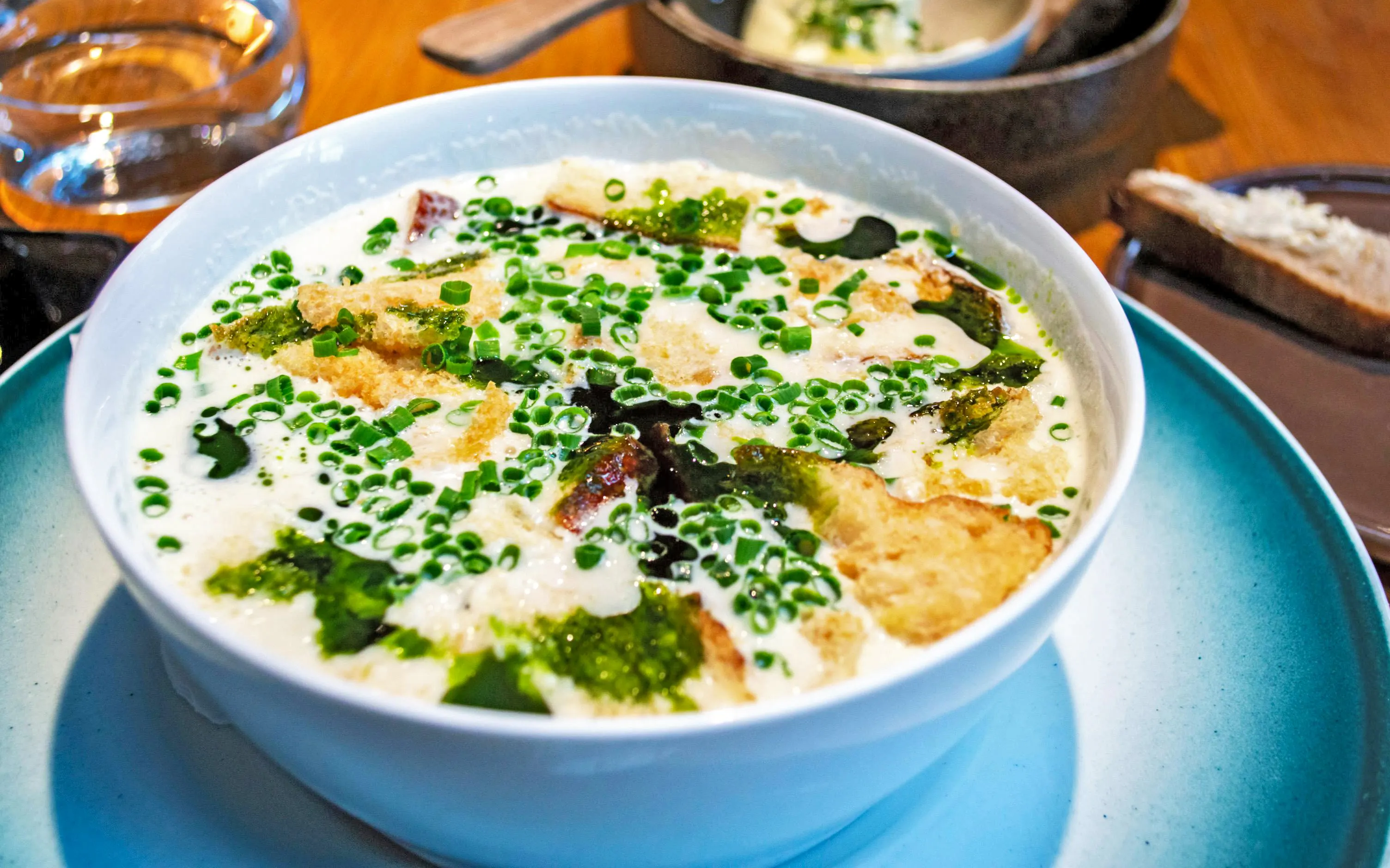 Traditional Norwegian fish soup with creamy broth, fish fillet, bread, and scallions in a white bowl.