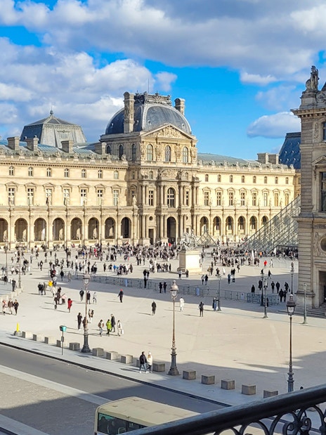 Louvre Museum exterior with courtyard and glass pyramid in Paris.