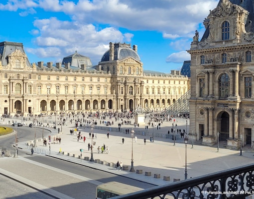 Exterior view of the Louvre Museum in Paris, showcasing its iconic glass pyramid entrance during daytime