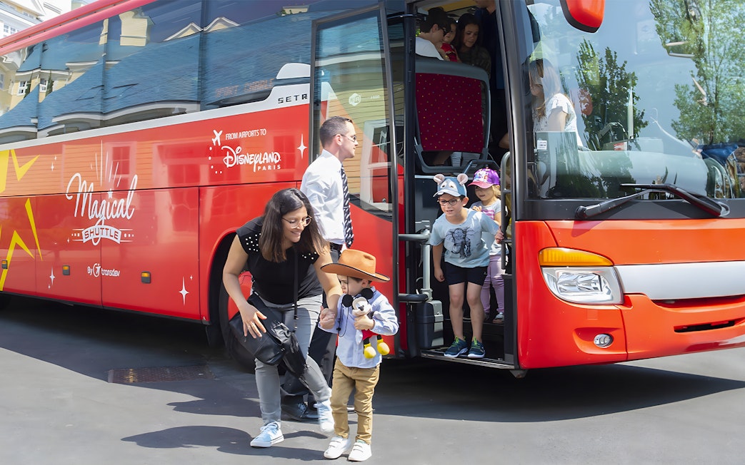 Families disembark Magic Shuttle bus at Disneyland Paris entrance.