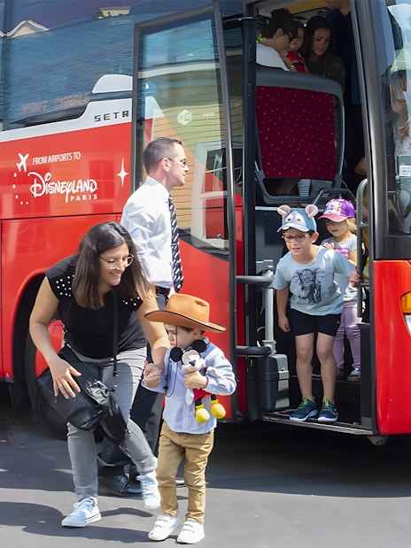Families disembark Magic Shuttle bus at Disneyland Paris entrance.