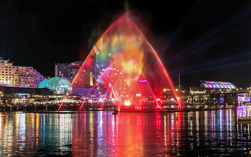 Vivid Sydney light show over water with city skyline in the background.