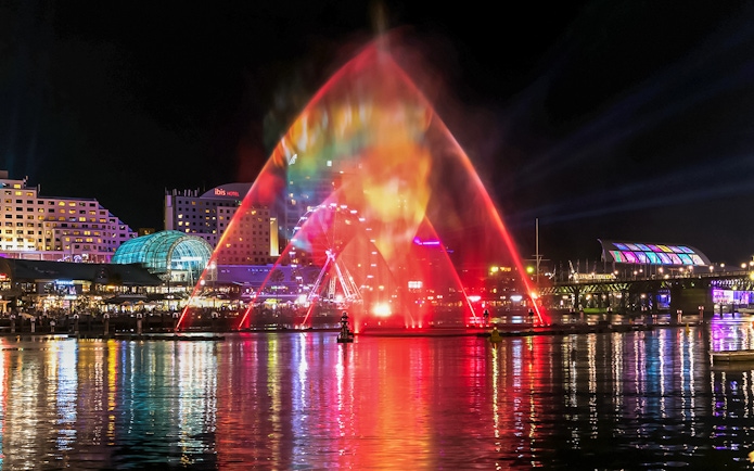 Vivid Sydney light show over water with city skyline in the background.