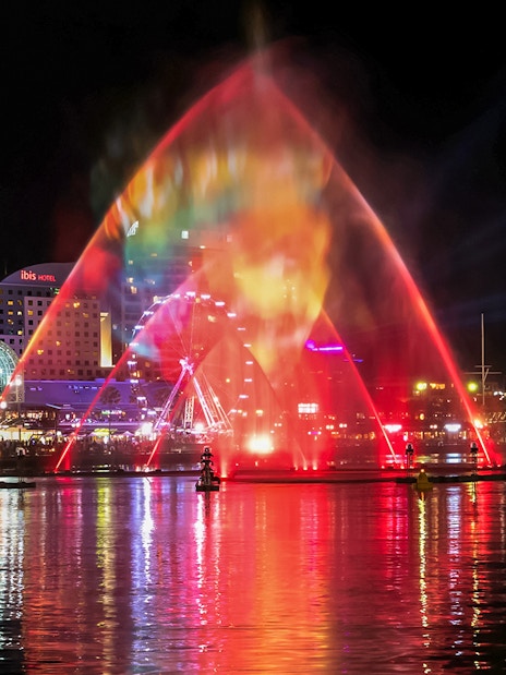 Vivid Sydney light show over water with city skyline in the background.