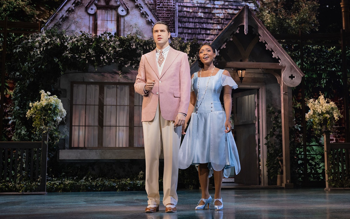 Actors in 1920s attire on stage in front of a cottage, related to The Great Gatsby.