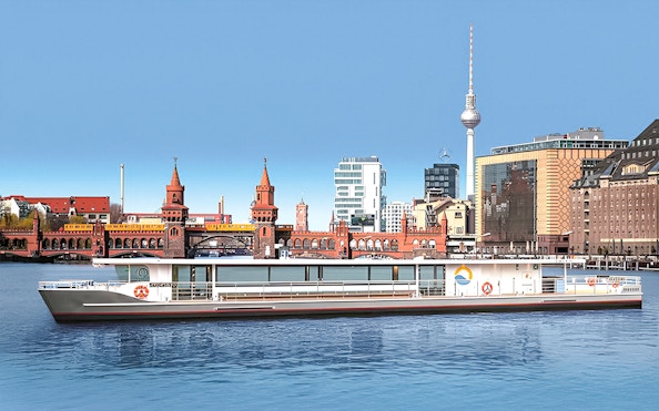 Solar boat cruising on the Spree River with Berlin's Oberbaum Bridge and TV Tower in the background.