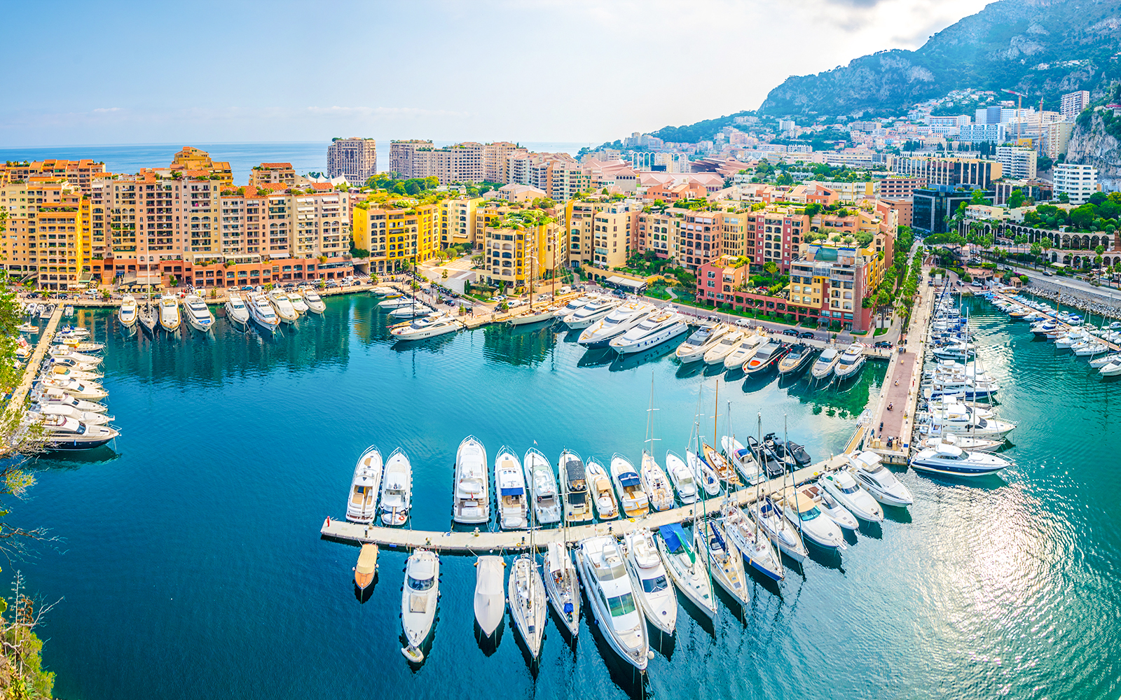 Yachts docked at Port de Fontvieille, Monaco with colorful buildings in the background.