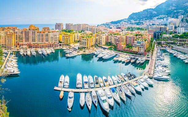 Yachts docked at Port de Fontvieille, Monaco with colorful buildings in the background.