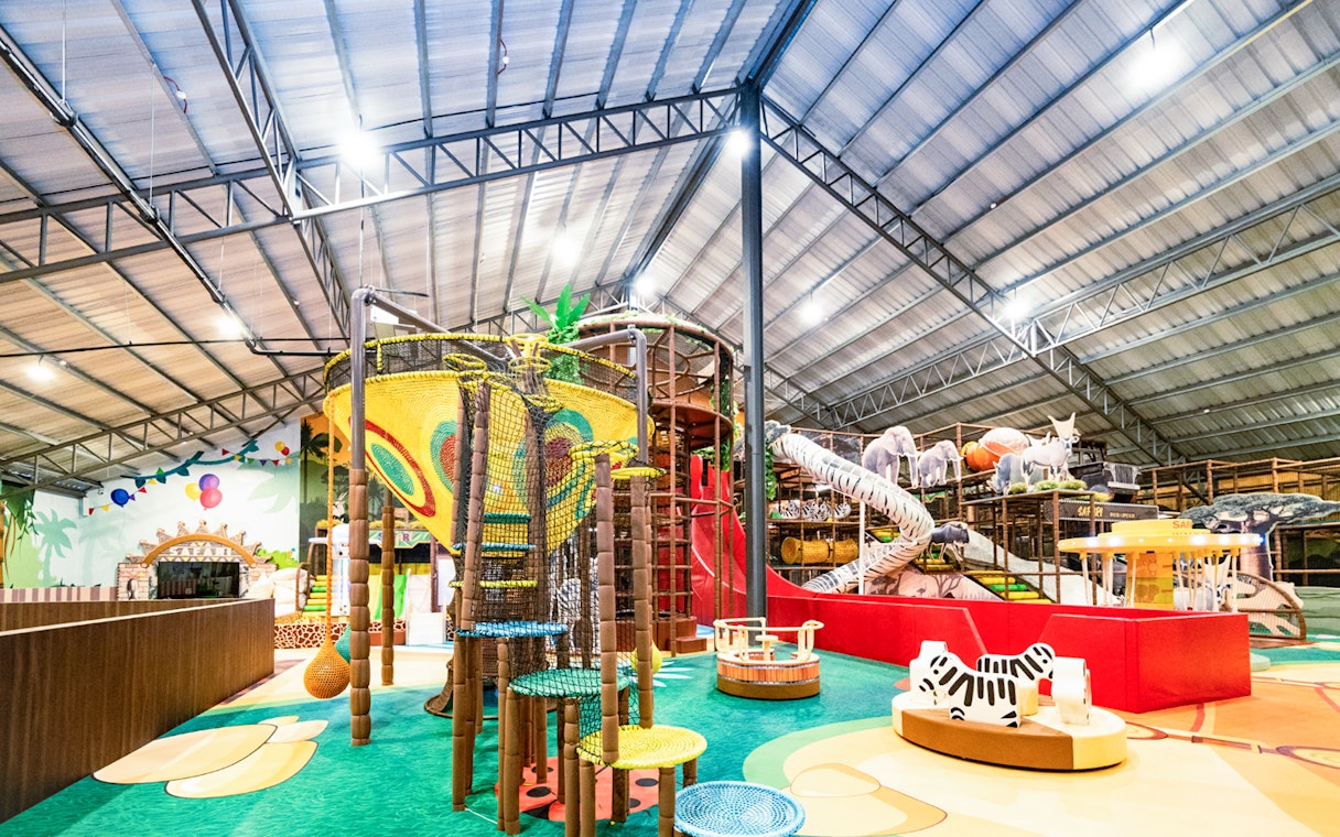 Indoor safari-themed playland with climbing structures and animal figures.