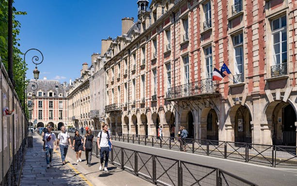 Tourists walking in Place des Vosges, Marais, Paris during a guided tour.