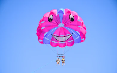 Parasailing with colorful parachute against clear blue sky.