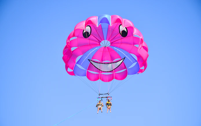 Parasailing with colorful parachute against clear blue sky.