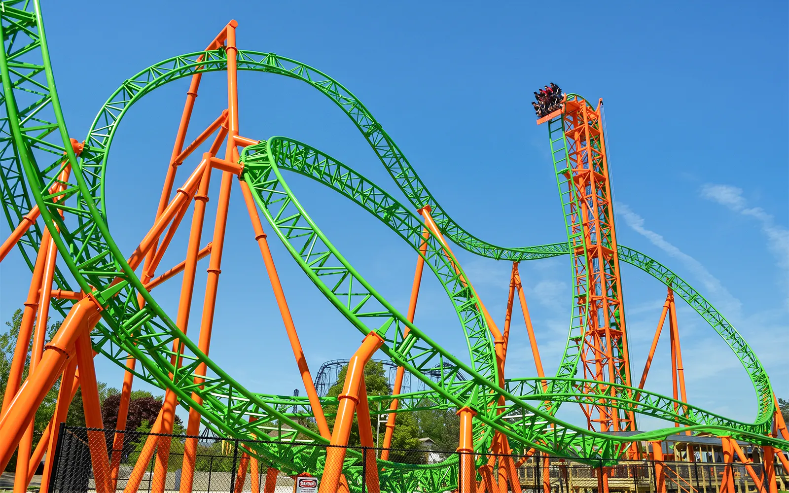 Roller coaster Tantrum at Six Flags Darien Lake with vibrant green and orange tracks.