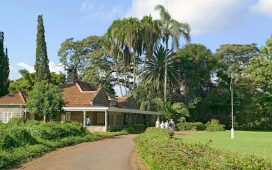 Karen Blixen Museum with visitors in lush garden, Nairobi, Kenya.