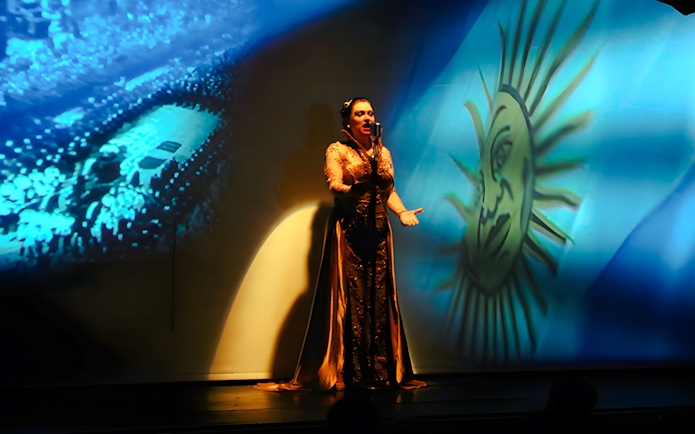 Singer performing at Piazzolla Tango Show in Buenos Aires with Argentine flag backdrop.