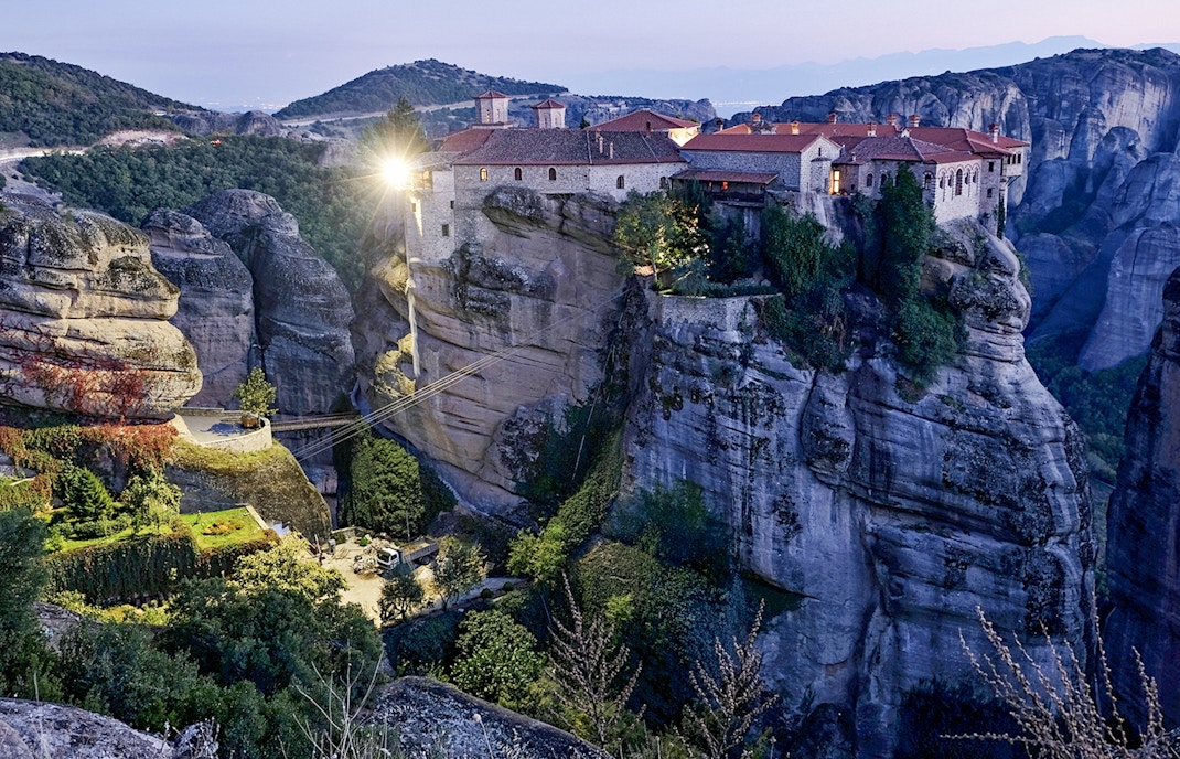 Monastery of Varlaam illuminated at night atop rock formations in Meteora, Greece.