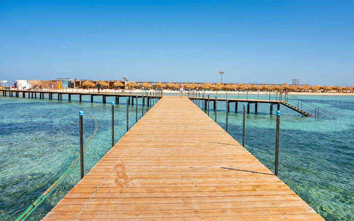 Wooden pier leading to Bianca Island beach in Hurghada with clear blue water.