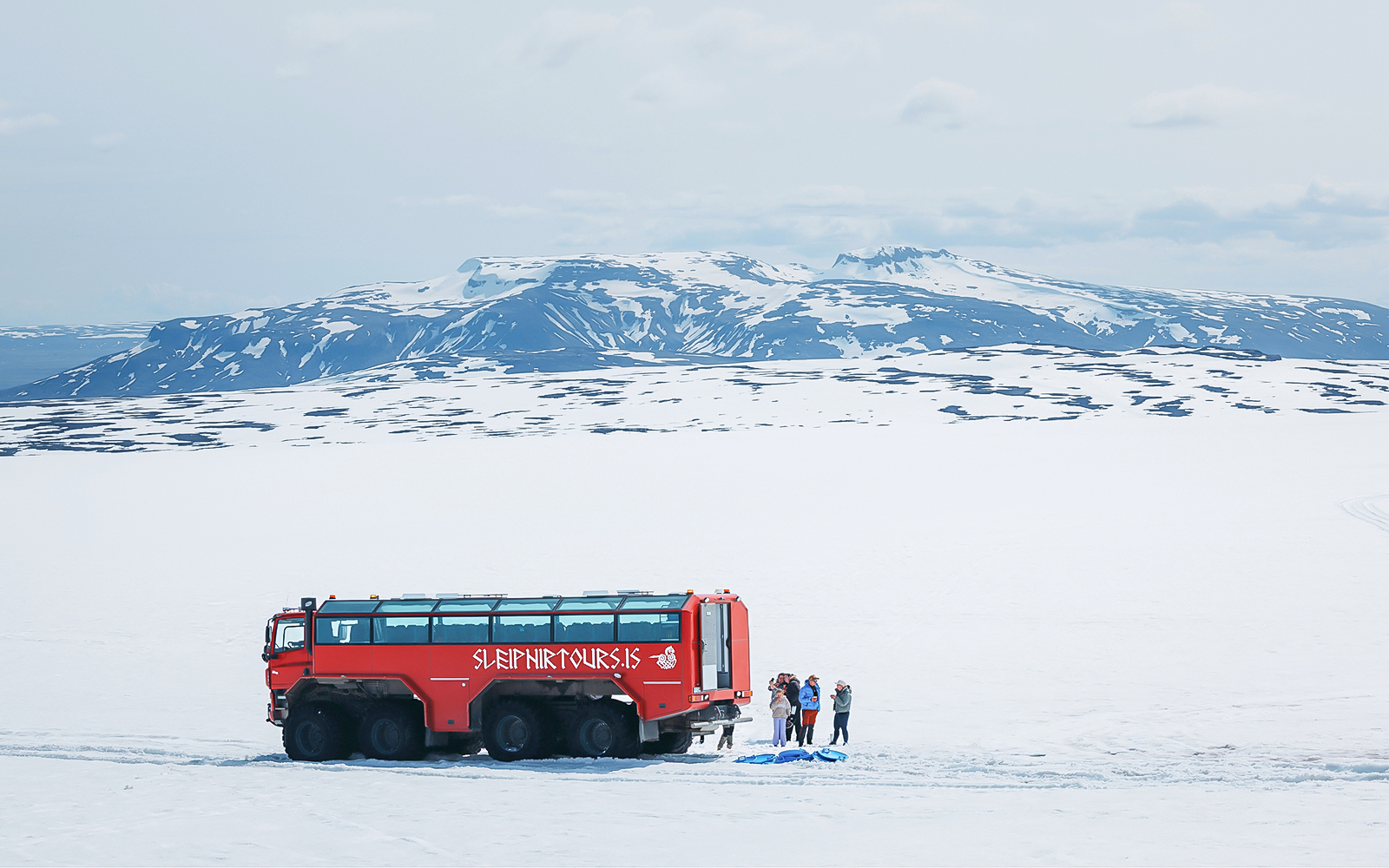 Red monster truck on Langjökull Glacier tour with tourists near Gullfoss, Iceland.