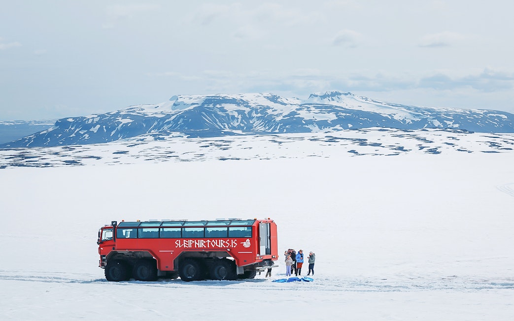 Red monster truck on Langjökull Glacier tour with tourists near Gullfoss, Iceland.
