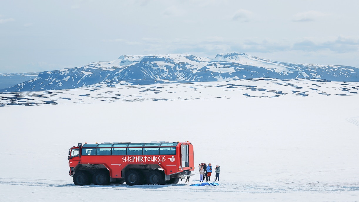 Red monster truck on Langjökull Glacier tour with tourists near Gullfoss, Iceland.