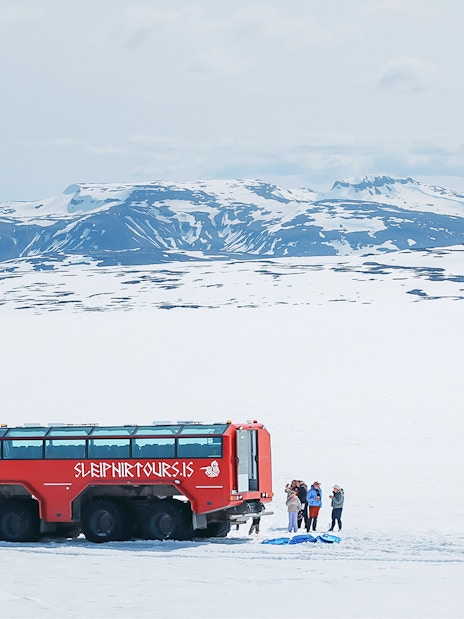 Red monster truck on Langjökull Glacier tour with tourists near Gullfoss, Iceland.