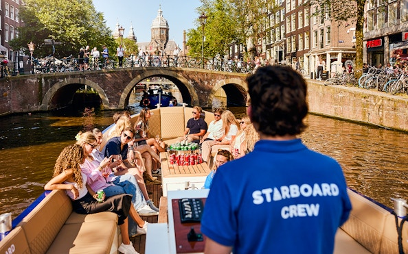 Guests enjoying a Luxury Canal Cruise in Amsterdam with a view of historic bridges.