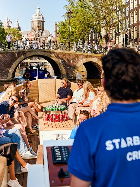 Guests enjoying a Luxury Canal Cruise in Amsterdam with a view of historic bridges.