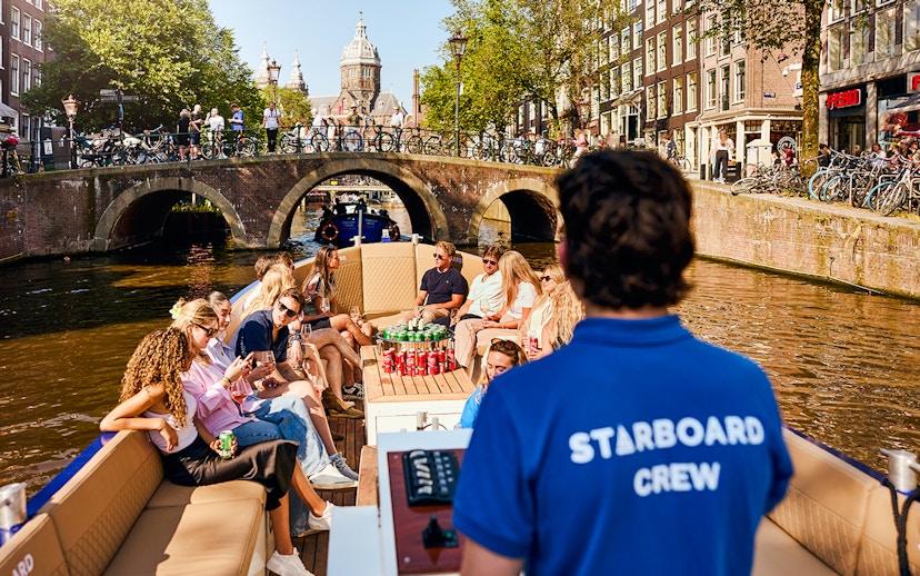 Guests enjoying a Luxury Canal Cruise in Amsterdam with a view of historic bridges.