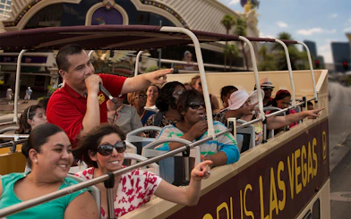 Tourists on Las Vegas hop-on hop-off bus pointing at attractions.