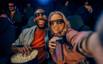 Couple enjoying popcorn and drinks at a movie theater.