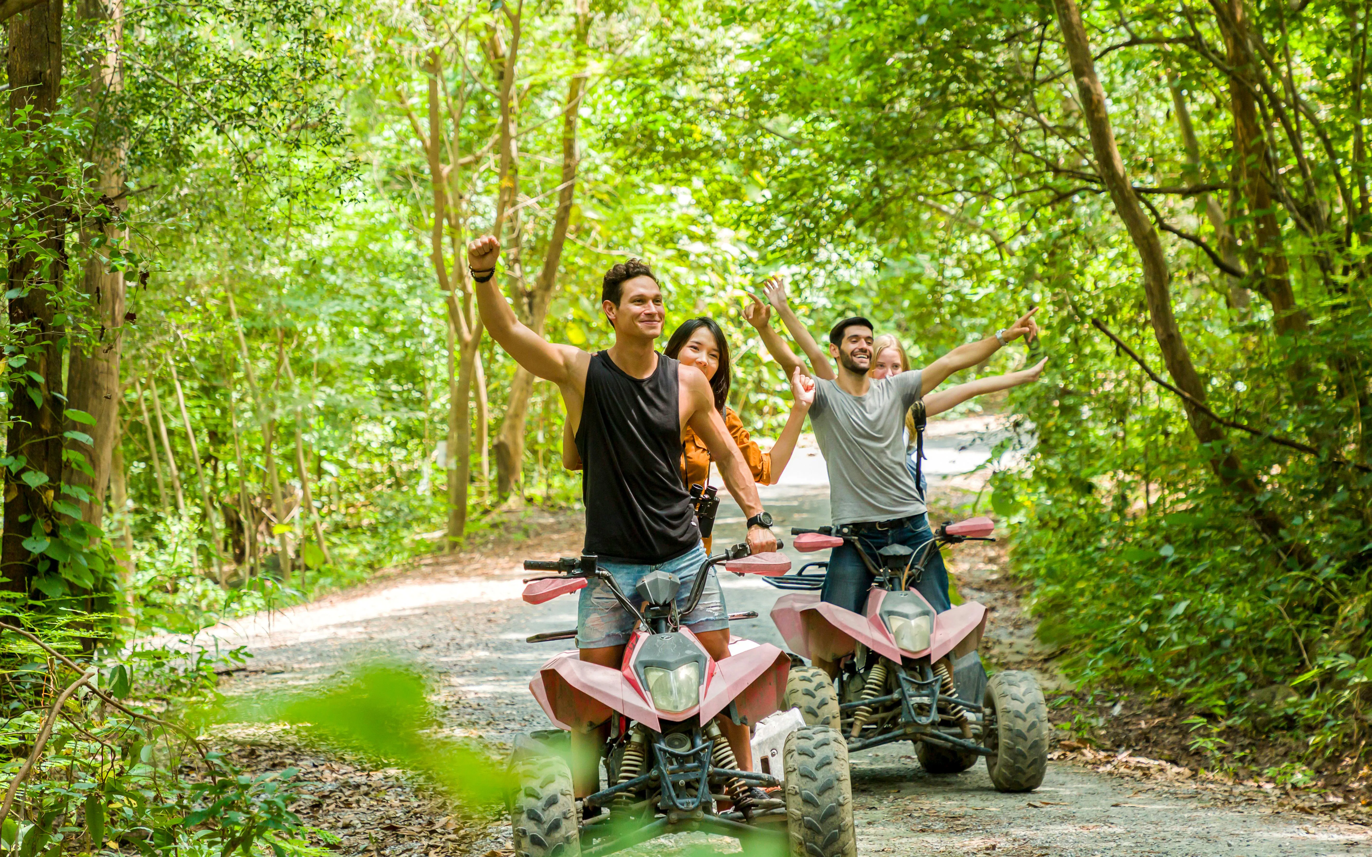 Young adults riding ATVs through a forest trail, enjoying an off-road adventure.