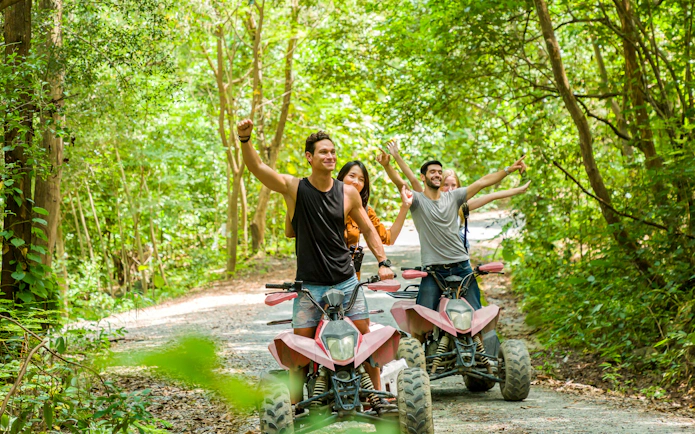 Young adults riding ATVs through a forest trail, enjoying an off-road adventure.