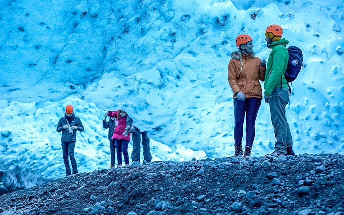 Visitors exploring a blue ice cave on a Crystal Ice Cave Tour.