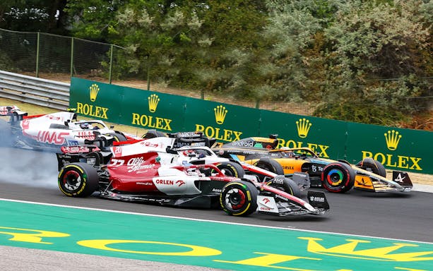 Formula 1 cars racing at the Hungarian Grand Prix with Rolex signage in the background.