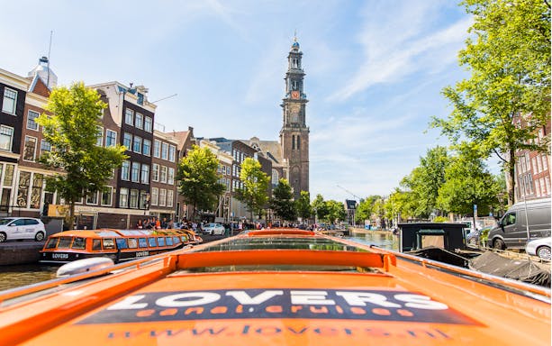 Amsterdam canal cruise boat with Westerkerk tower in the background.
