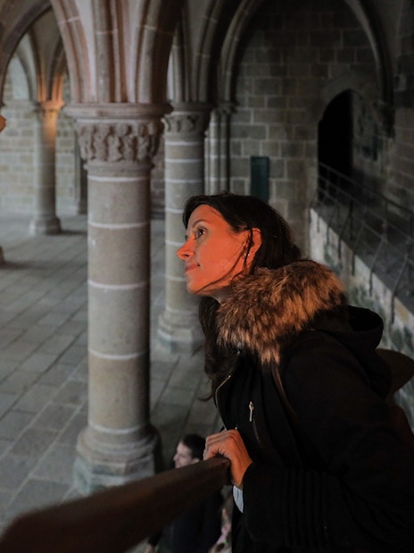 Visitor exploring the interior columns of Mont St. Michel's Abbey during a full day tour from Paris.